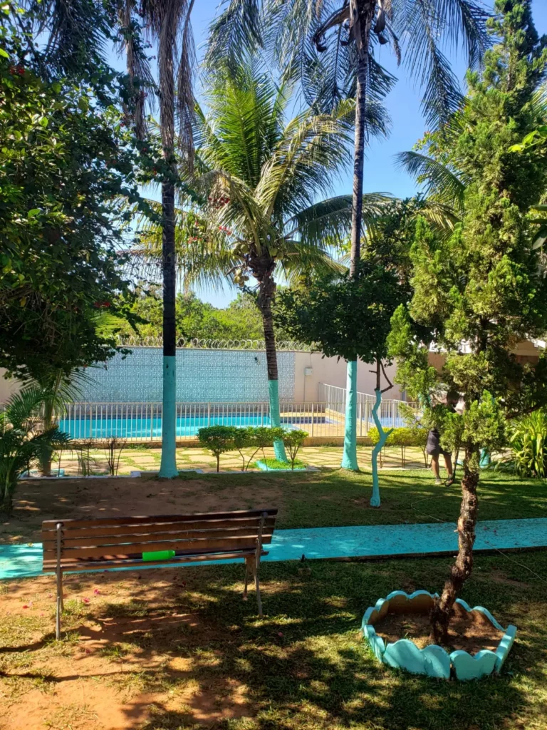 Jardim arborizado com bancos e piscina na Residência Terapêutica Luz do Sol, em Aparecida de Goiânia